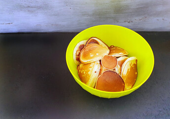 homemade pancakes in a bright green bowl, on a dark background