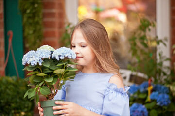 little blond girl in blue dress with flowers nearby flowers store