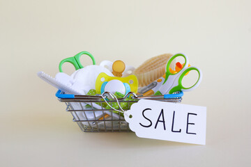 Shopping basket with baby care items - scissors, hairbrushes, pacifiers, thermometer, cotton pads,...