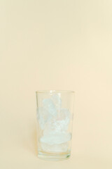 베이지 배경에서 촬영한 얼음이 담긴 유리컵
