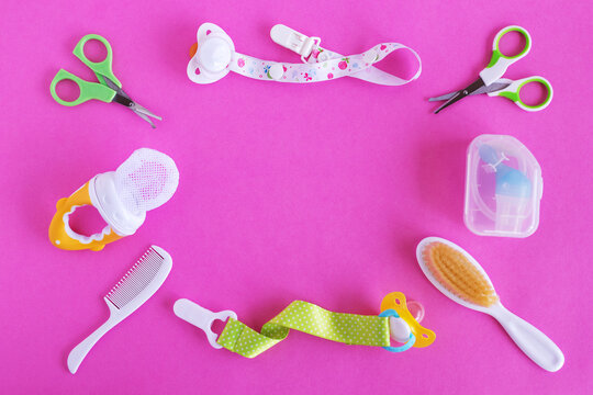 Flat lay on baby care items - scissors, hairbrushes, pacifiers, pacifier holders, nasal aspirator and nibbler- on pink background with copy space. Concept of medicine and hygiene of the child.