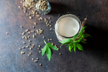 Fototapeta na wymiar Homemade vegan milk from hemp seeds in a glass jar on a dark concrete background. Non-dairy milk. Healthy lifestyle.