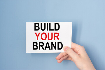 Hand holding card with inscription Build your brand.