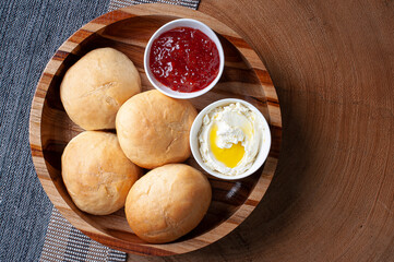 
Homemade bread in a wooden bowl accompanied by curd and jam. Top view