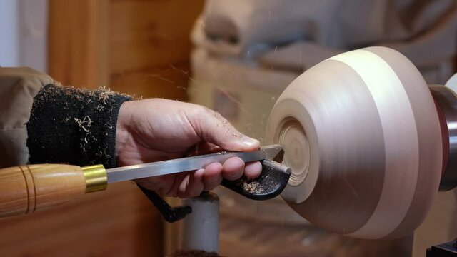 Craftsman works with workpiece in authentic workshop. Woodworker handles wood by bench. Making beautiful wooden handmade dish. Creation of unusual plate. Carpenter cuts wood by graver in soft focus