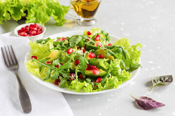 Avocado and pomegranate salad on a white plate on a gray background. Healthy vegetarian food