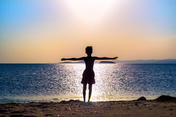 little kid at beach, arms wide open in front of sunset, feels total freedom