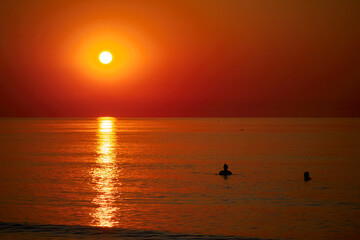 Silhouette of a couple swimming in the sea at sunrise