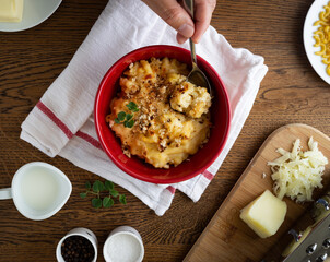Homemade Baked Mac and Cheese on a Wooden Table with Ingredients Placed Around it.