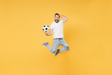 Fototapeta na wymiar Screaming bearded man guy football fan in white t-shirt isolated on yellow background. People sport family leisure concept. Cheer up support favorite team with soccer ball, jumping, put hand on head.