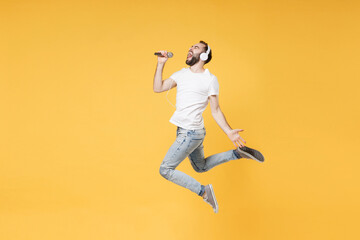 Funny young bearded man guy in white casual t-shirt posing isolated on yellow background. People...