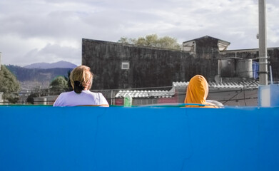 two people back sitting in a terrace looking at a poor view while confinament 