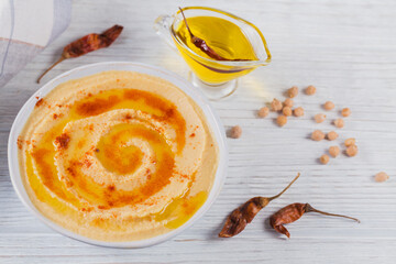 Fototapeta premium Healthy snack from crisp bread with hummus, olive oil and paprika on white wooden background
