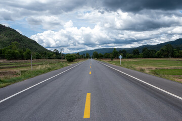 Fototapeta premium A road with a mountain and sky background in Thailand's countryside