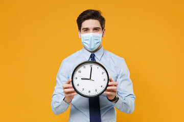 Young business man in classic blue shirt tie sterile face mask isolated on yellow background....