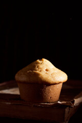 Homemade muffin cupcake lies on old book on black background
