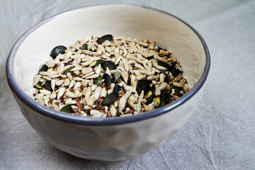 pumpkin, sunflower, sesame, Chia and flax seeds in a beige round plate side view on a light linen tablecloth . vegan products