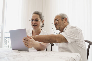Obraz premium The elderly couple trying to use the tablet show each other something on the screen. old couple is trying to talk to their grandchildren. elders enjoying with benefits of technology