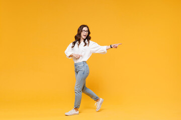 Fototapeta na wymiar Side view of excited young brunette business woman in white shirt glasses isolated on yellow background. Achievement career wealth business concept. Mock up copy space. Pointing index fingers aside.