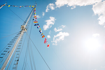 Sailboat mast without veil with nautical signs flags, space for copy text.