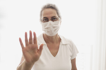  Elderly woman wearing a mask expressing her hand not approaching her.