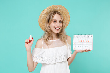 Smiling young woman girl in white dress hat hold periods calendar for checking menstruation days sanitary tampon isolated on blue turquoise background studio. Medical healthcare gynecological concept.