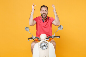 Irritated young bearded man guy in casual summer clothes driving moped isolated on yellow background. Driving motorbike transportation concept. Mock up copy space. Spreading hands screaming swearing.