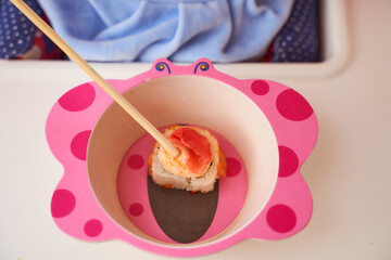 Children's cup for food in which lies one rice Japanese roll