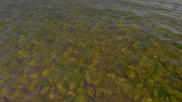 Droen flying over clear water with rockey bottom.