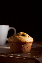 Homemade muffin cupcake lies on old book on black background