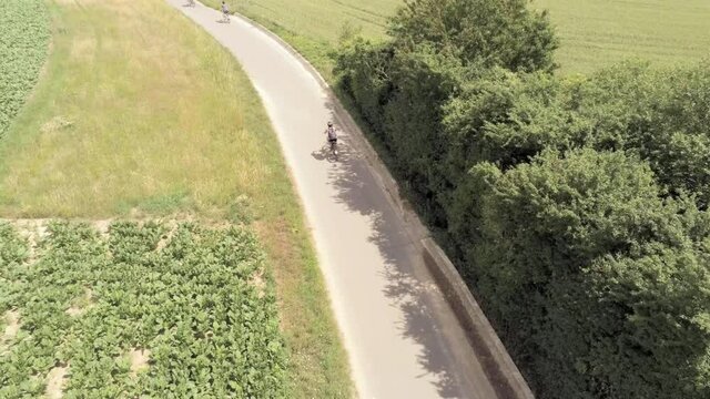 A single rider quickly catches up to a larger group of bicyclists, drought stricken fields, aerial