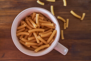 Yellow pasta lies on a brown table. Close-up.