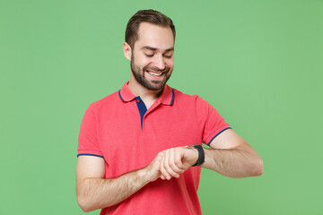 Smiling young bearded man guy in casual red pink t-shirt posing isolated on green wall background...