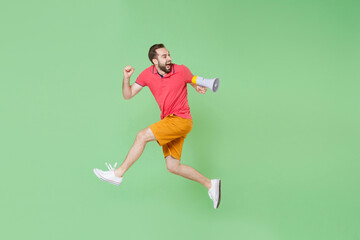 Fototapeta na wymiar Crazy young bearded man guy in casual red pink t-shirt posing isolated on green background studio portrait. People lifestyle concept. Mock up copy space. Jumping like running, scream in megaphone.