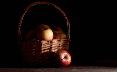 Braided basket with red apples on a black background