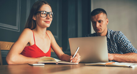 Serious freelancer using computer working with colleague taking notes