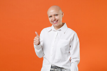 Smiling young bald business woman girl wearing white shirt posing isolated on orange wall background studio portrait. Achievement career wealth business concept. Mock up copy space. Showing thumb up.