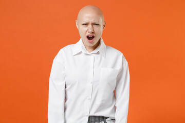 Shocked worried young bald business woman girl in white shirt posing isolated on orange background studio portrait. Achievement career wealth business concept. Mock up copy space. Keeping mouth open.