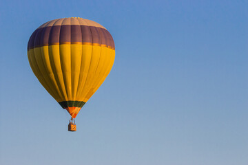 Kyiv, Ukraine - 06/26/2020: Hot air balloon in clear summer sky. Yellow balloon on blue background. Bright geometric design. Summer leisure. Hot air balloon in flight with copy space.