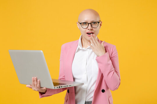 Amazed Young Bald Business Woman In White Shirt Pink Jacket Glasses Isolated On Yellow Background. Achievement Career Wealth Business Concept. Working On Laptop Pc Computer, Covering Mouth With Hand.