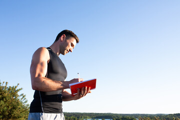 Fitness trainer writing in diary in countryside