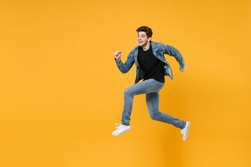 Fototapeta na wymiar Excited young man guy 20s wearing casual denim clothes posing isolated on yellow wall background studio portrait. People sincere emotions lifestyle concept. Mock up copy space. Jumping like running.