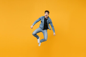 Fototapeta na wymiar Excited young man guy 20s wearing casual denim clothes posing isolated on yellow wall background studio portrait. People sincere emotions lifestyle concept. Mock up copy space. Jumping, having fun.