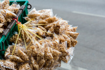 Naklejka premium Pork snack in a plastic bag, hanging in bulk. Thai style Pork snack or crispy pork skin, in plastic bag ready for sale at the market