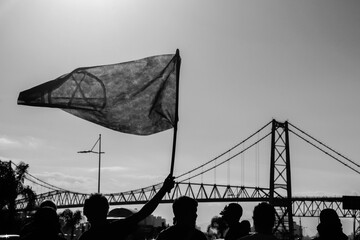 Young anarchists with black flags protesting in front of the Hercílio Luz Bridge, Florianópolis,...