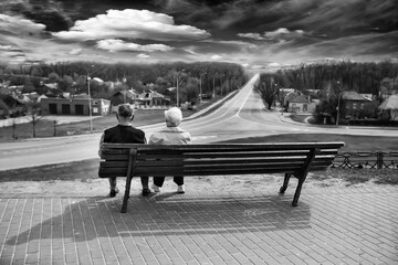 Older people sit on a bench and look into the distance - 361169178