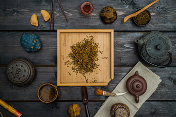 Chinese tea on square light board with different tea tools and figurines on black wooden table. View from above