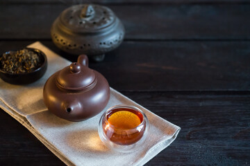 Teapot, incense and bowl with tea on light fabric and black wooden table