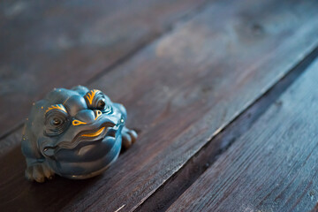 Clay figurine blue china frog on dark wooden table