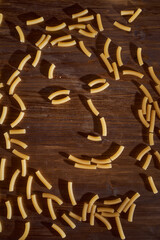 Yellow pasta lies on a brown table. Close-up.